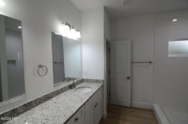 bathroom featuring a tile shower, vanity, and hardwood / wood-style flooring