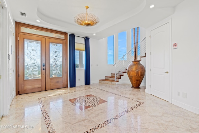 entryway with a tray ceiling and french doors