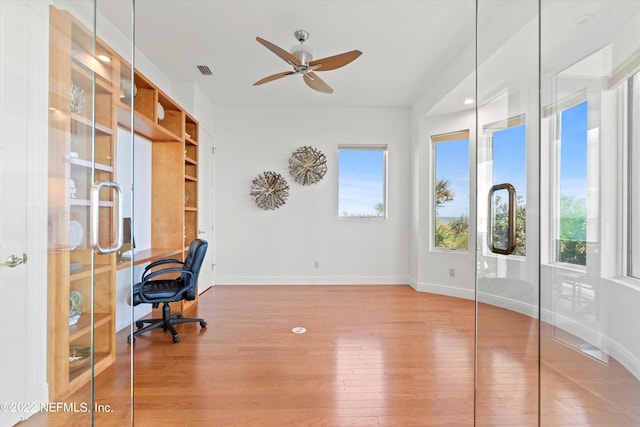 home office with wood-type flooring and ceiling fan