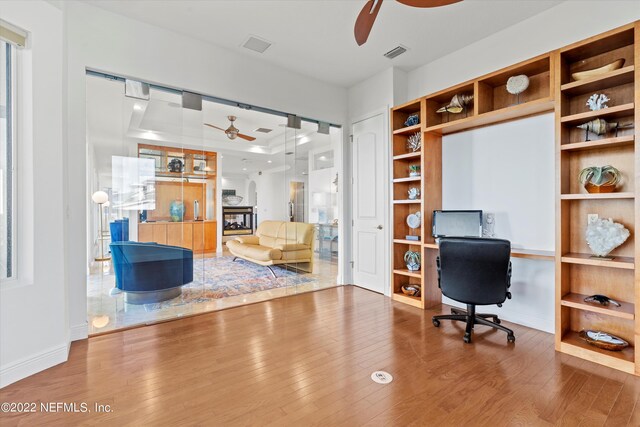 unfurnished office with ceiling fan and hardwood / wood-style flooring