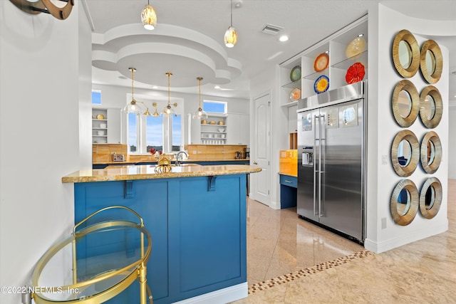 kitchen featuring a kitchen bar, kitchen peninsula, hanging light fixtures, and built in fridge