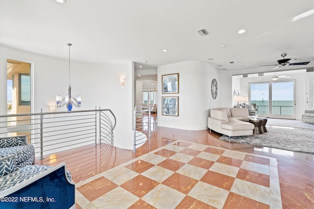 living room with a water view and ceiling fan with notable chandelier