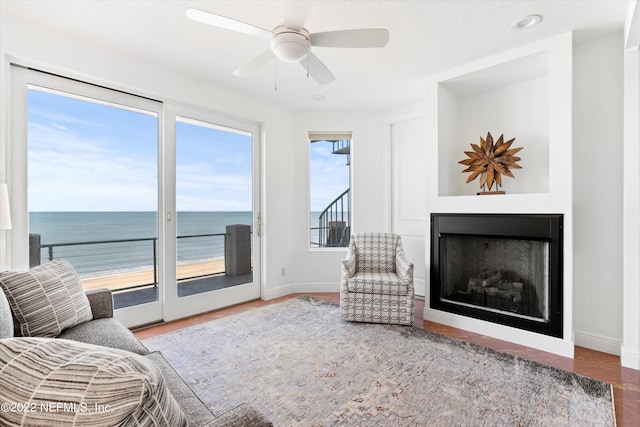 living room with a textured ceiling, a water view, and ceiling fan