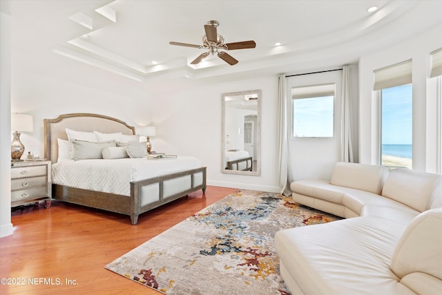 bedroom featuring hardwood / wood-style flooring, a raised ceiling, and ceiling fan