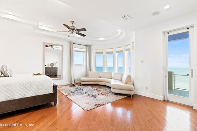 bedroom featuring access to exterior, ceiling fan, a water view, and light hardwood / wood-style floors