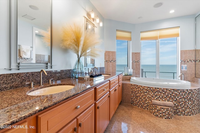 bathroom with vanity, plenty of natural light, a water view, and tiled tub