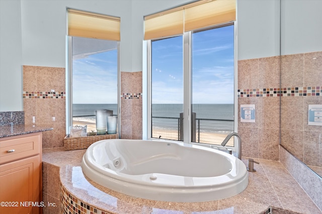 bathroom featuring tiled bath, vanity, a water view, and tile walls