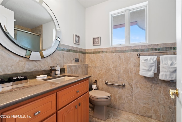 bathroom with tile patterned flooring, vanity, tile walls, and toilet