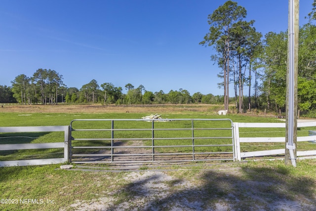 view of gate with a yard and a rural view