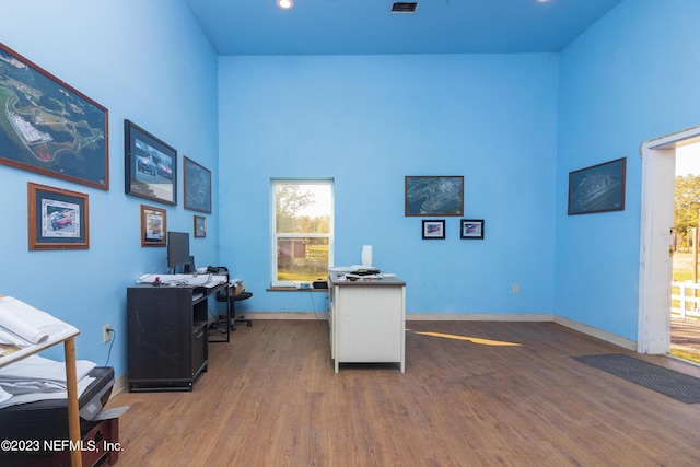 home office with a high ceiling and wood-type flooring