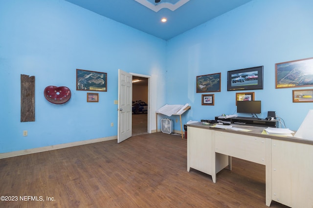 office space featuring a towering ceiling and dark hardwood / wood-style floors