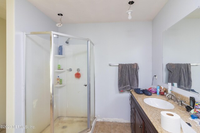 bathroom featuring tile patterned flooring, a shower with door, and vanity