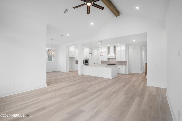 unfurnished living room featuring high vaulted ceiling, ceiling fan with notable chandelier, beamed ceiling, and light hardwood / wood-style floors