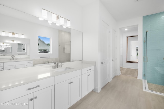 full bath featuring a stall shower, two vanities, and a sink