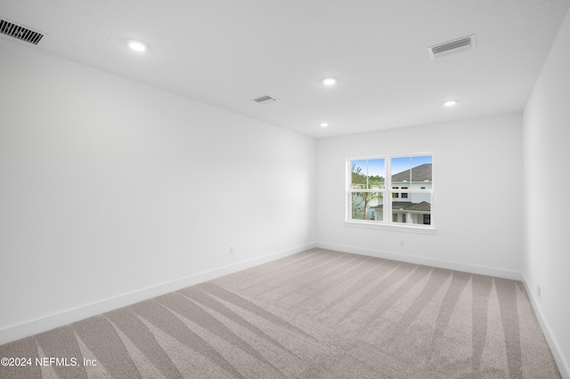 carpeted spare room featuring baseboards, visible vents, and recessed lighting