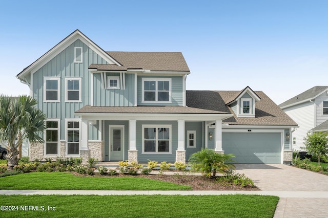 view of front of home featuring a porch, a garage, and a front lawn