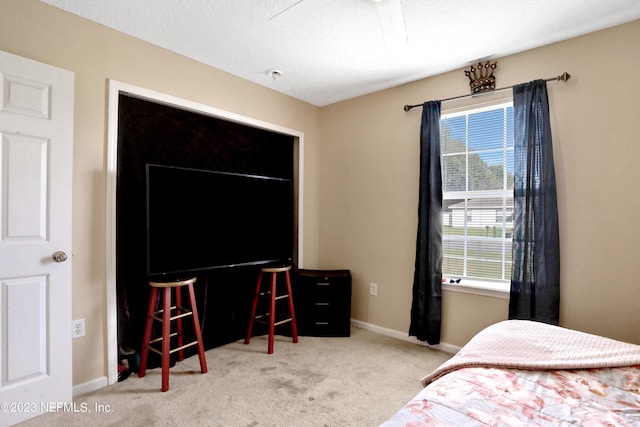 bedroom with a textured ceiling, ceiling fan, and light colored carpet