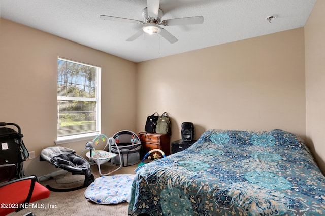 carpeted bedroom featuring ceiling fan and a textured ceiling