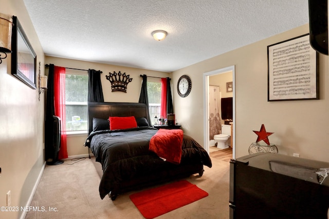 bedroom with light colored carpet, a textured ceiling, and ensuite bathroom