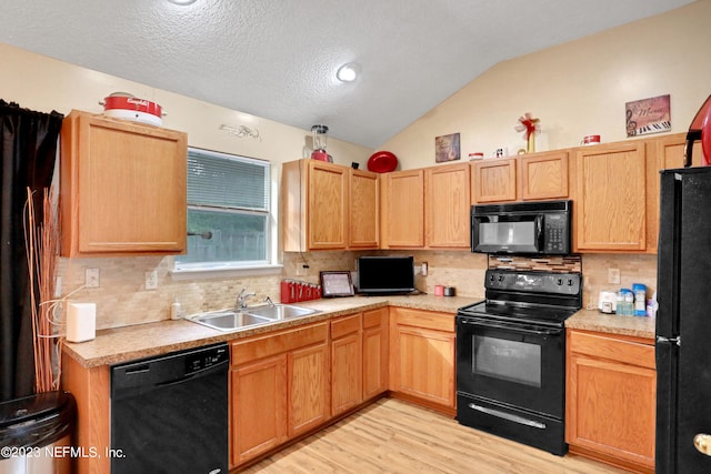 kitchen featuring sink, lofted ceiling, light hardwood / wood-style flooring, black appliances, and backsplash