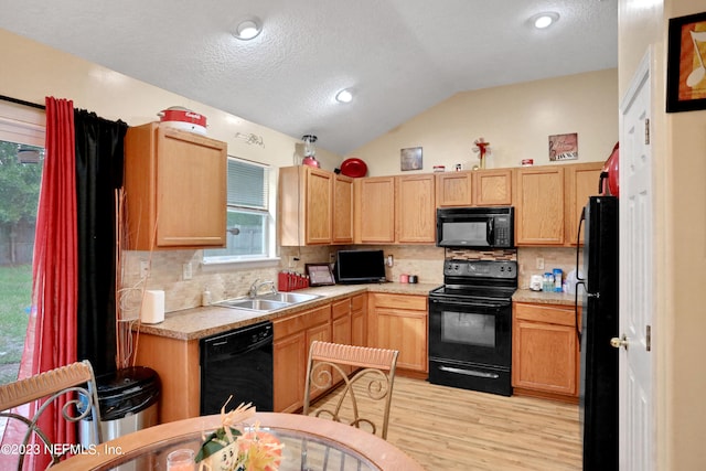 kitchen with black appliances, lofted ceiling, sink, and plenty of natural light