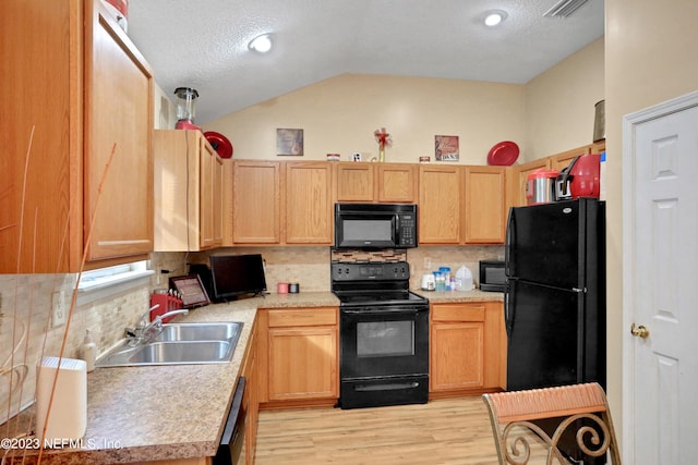 kitchen with black appliances, lofted ceiling, decorative backsplash, and sink