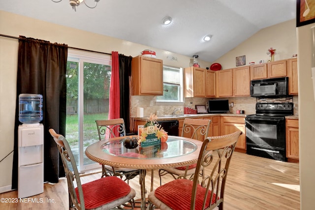 kitchen featuring light wood-type flooring, vaulted ceiling, a healthy amount of sunlight, and black appliances