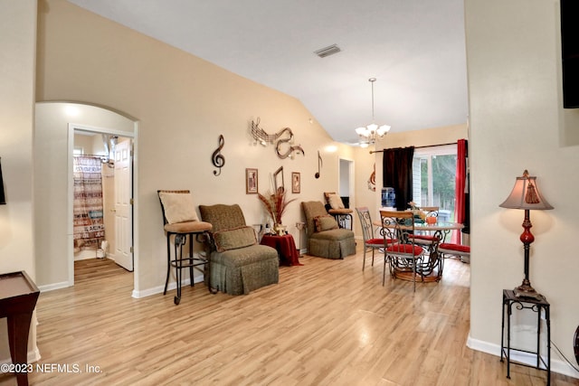 living room featuring light wood-type flooring, vaulted ceiling, and a chandelier