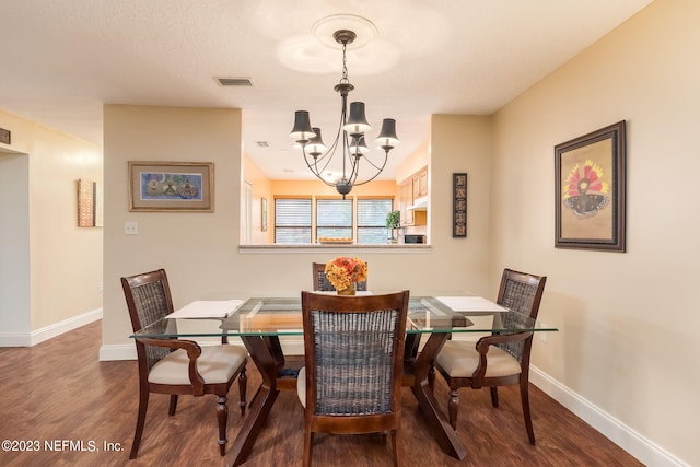 dining space featuring dark wood-type flooring and an inviting chandelier