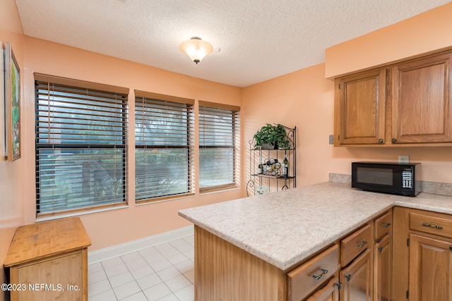 kitchen featuring kitchen peninsula, light tile patterned floors, and a textured ceiling