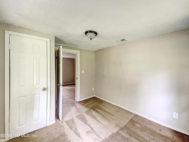 empty room with a textured ceiling and light carpet