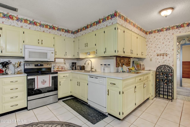 kitchen with white appliances, sink, a textured ceiling, and light tile patterned floors