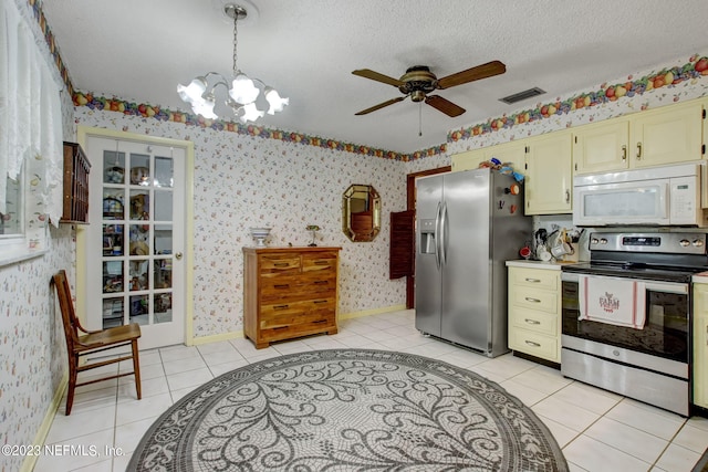 kitchen with stainless steel appliances, decorative light fixtures, a textured ceiling, and light tile patterned floors