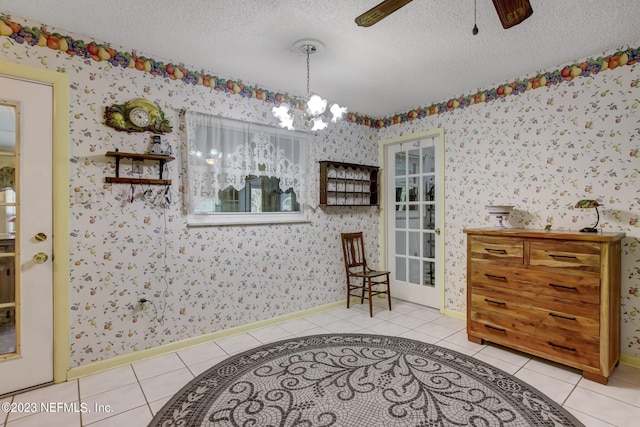 interior space with light tile patterned floors, ceiling fan with notable chandelier, and a textured ceiling