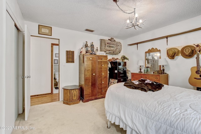 bedroom with light colored carpet, a notable chandelier, and a textured ceiling