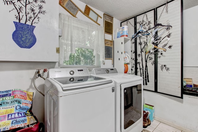 laundry area with washer and clothes dryer, a textured ceiling, and light tile patterned flooring