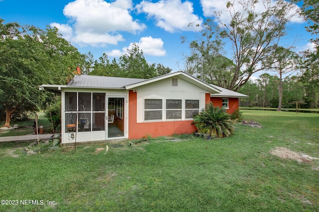 rear view of house with a sunroom and a lawn