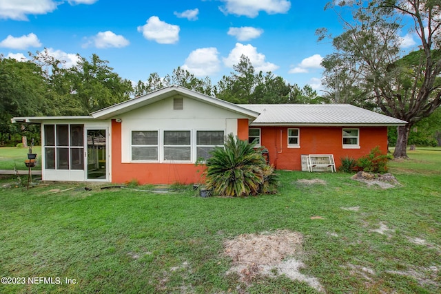 rear view of property with a sunroom and a lawn