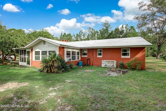 rear view of house featuring a yard and a sunroom