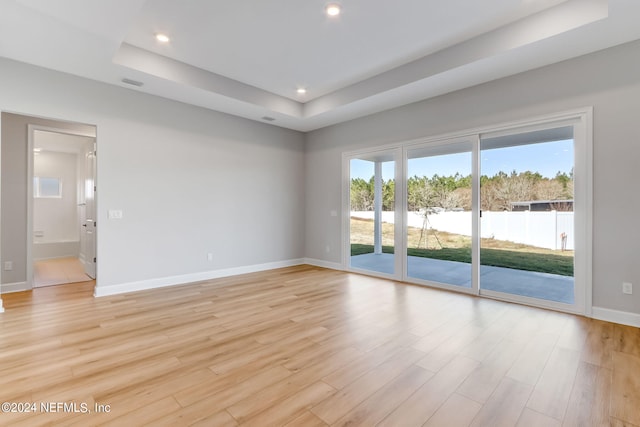 unfurnished room featuring a tray ceiling and light hardwood / wood-style floors