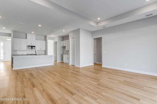 unfurnished living room with light wood-type flooring and sink