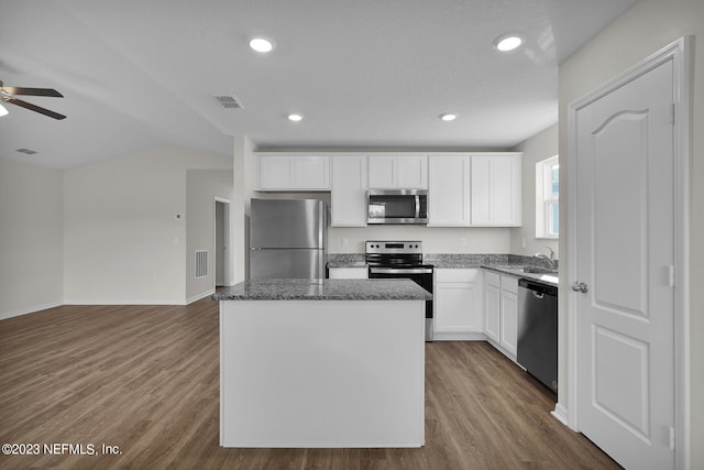 kitchen featuring stainless steel appliances, white cabinetry, a center island, hardwood / wood-style floors, and ceiling fan