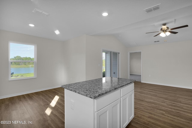 kitchen featuring dark hardwood / wood-style floors, a center island, white cabinets, dark stone counters, and ceiling fan