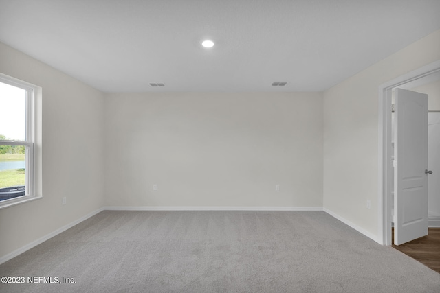 unfurnished room featuring plenty of natural light and dark colored carpet