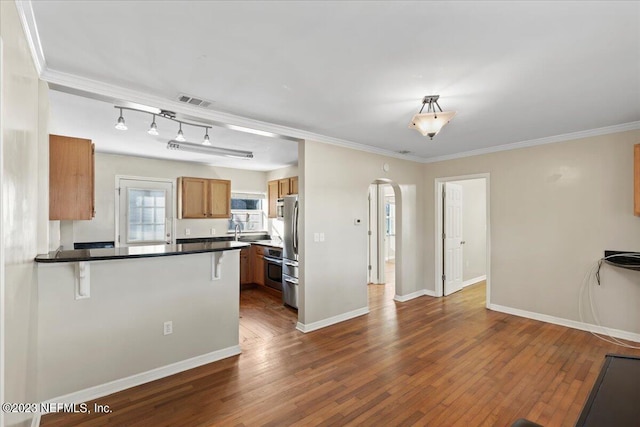 kitchen with stainless steel fridge, sink, kitchen peninsula, dark wood-type flooring, and a breakfast bar