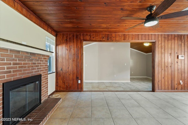 unfurnished living room with ceiling fan, wood ceiling, wood walls, ornamental molding, and a fireplace