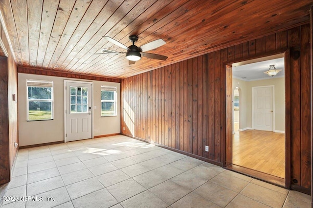 unfurnished room with ceiling fan, light tile patterned floors, wooden walls, wooden ceiling, and crown molding