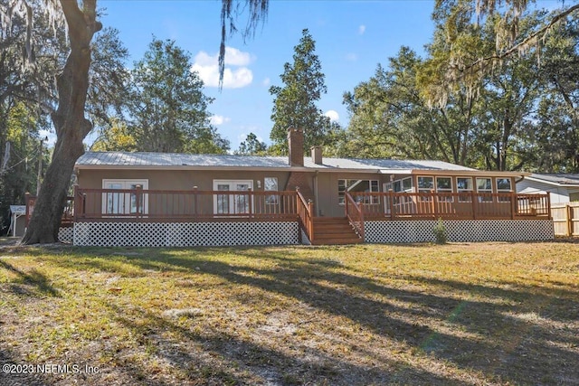 back of house featuring a wooden deck and a lawn