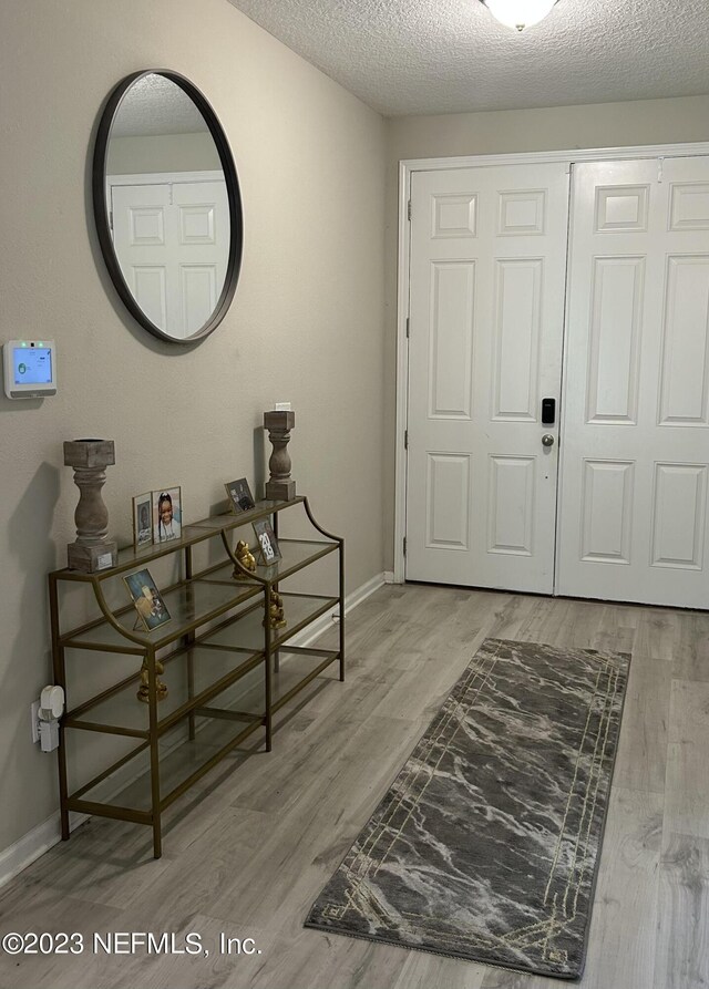 hallway with light hardwood / wood-style floors and a textured ceiling