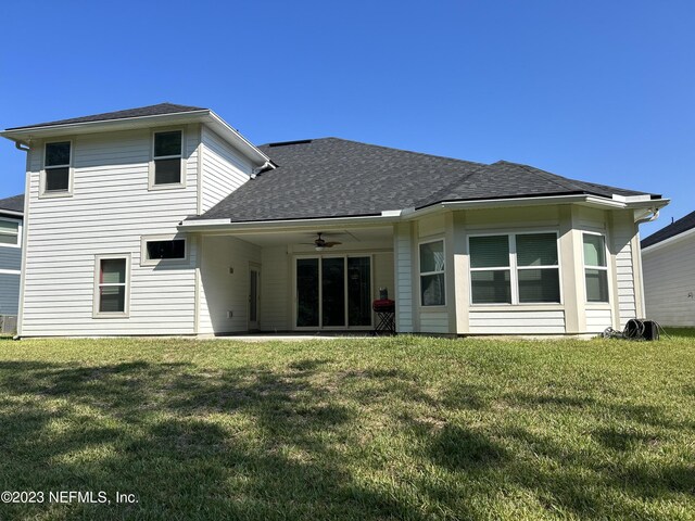 back of house featuring a lawn and ceiling fan